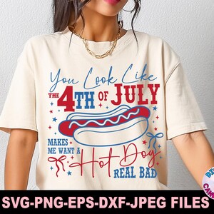 May include: Cream-colored t-shirt with a Fourth of July theme. The shirt features the text "You Look Like the 4th of July" and "Makes Me Want a Hot Dog Real Bad" with a hot dog graphic in red, white, and blue.