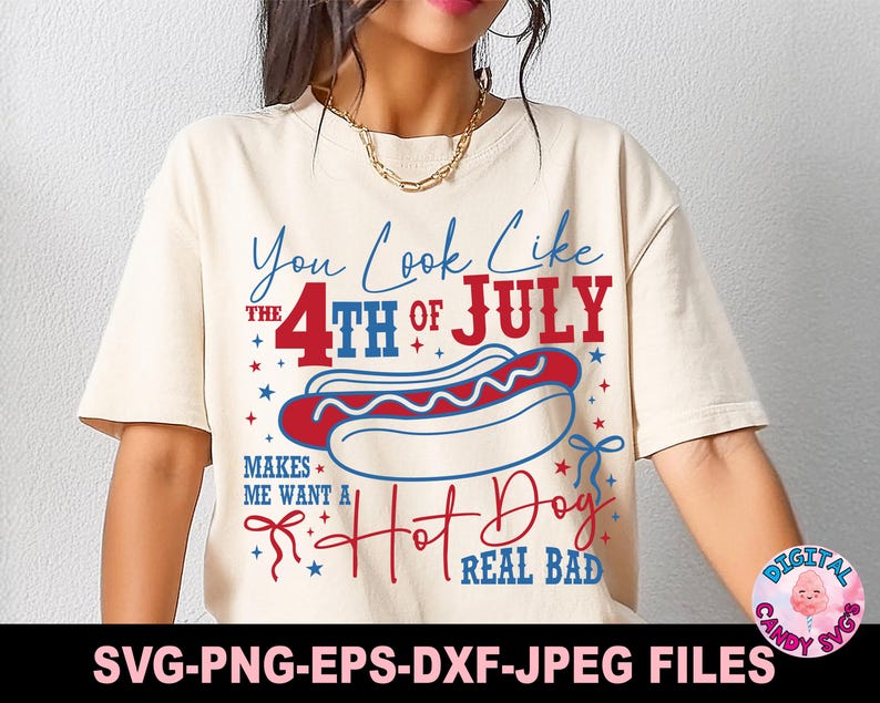 May include: Cream-colored t-shirt with a Fourth of July theme. The shirt features the text "You Look Like the 4th of July" and "Makes Me Want a Hot Dog Real Bad" with a hot dog graphic in red, white, and blue.