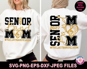 Può includere: Una felpa bianca con la scritta "SENIOR Band MOM 2027" in nero e oro. Il design include un cuore a forma di nota musicale e l'hashtag #THELASTBANDSEASON. Anche il retro della felpa presenta lo stesso design.