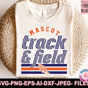 May include: Cream-colored t-shirt with the words "MASCOT track & field" in blue and orange. A winged shoe graphic is below the text. The shirt is folded on a woven wicker surface. DigitalCandy font included.
