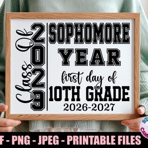 May include: A rectangular wooden frame containing a white sign with black text that reads Class of 2029, Sophomore Year, first day of 10th Grade, and 2026-2027. The design uses a mix of bold block lettering and a cursive script font style.