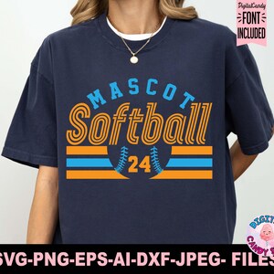 May include: A navy blue t-shirt with a graphic design of a softball with the text "MASCOT Softball 24" in orange and blue.