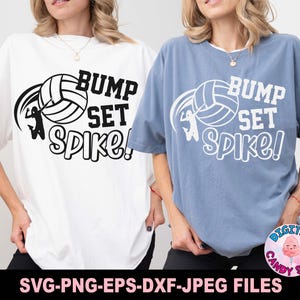 Puede incluir: Dos camisetas blancas y azules con el texto "Bump Set Spike!" y un gráfico de voleibol. Las camisetas están sobre un fondo blanco.