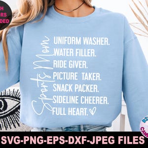 May include: Light blue sweatshirt with the text "Sports Mom" and a list of duties: Uniform Washer, Water Filler, Ride Giver, Picture Taker, Snack Packer, Sideline Cheerer, Full Heart.