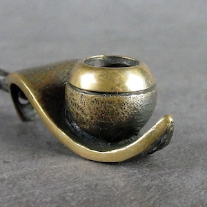 May include: A small, abstract bronze sculpture of a snail with a textured shell and a smooth, gold-colored body.