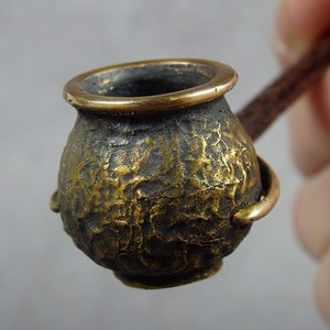 Könnte beinhalten: Eine kleine, antike, messingfarbene Pfeife mit einem strukturierten Kopf und einem Holzstiel.