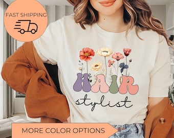 May include: White t-shirt with a floral design and the text "HAIR stylist" in colorful, bubble-like letters.