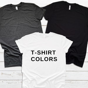 May include: Three t-shirts in different colors: dark grey, black, and white. The white t-shirt has the text "T-SHIRT COLORS" printed on it.