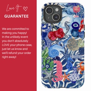 May include: A colourful phone case with a blue and white background. The case features a variety of images, including seashells, starfish, seahorses, cherries, and a blue evil eye. The text "Greece" is visible in the bottom right corner.