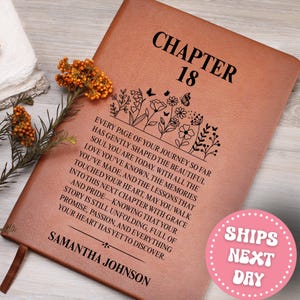 May include: A brown leather journal with the text "CHAPTER 18" and a floral design. The journal includes a personalized name and a message about life's journey. A pink sticker with the text "SHIPS NEXT DAY" is visible.