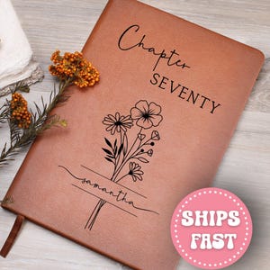 May include: A brown leather journal with the words "Chapter Seventy" and the name "Samantha" printed on the cover. A floral design is also printed on the cover. A pink circle with the words "SHIPS FAST" is in the bottom right corner.