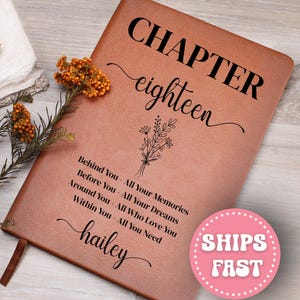 May include: A brown leather journal with the words "CHAPTER eighteen" in black script. Below, it reads "Behind You - All Your Memories, Before You - All Your Dreams, Around You - All Who Love You, Within You - All You Need, hailey." A pink sticker says "SHIPS FAST."