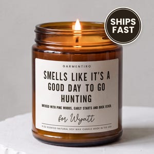 May include: A 9 ounce scented natural soy wax candle in an amber glass jar with a white label that reads: GARMENTIRO, SMELLS LIKE IT'S A GOOD DAY TO GO HUNTING, INFUSED WITH PINE WOODS, EARLY STARTS AND BUCK FEVER, for Wyatt.