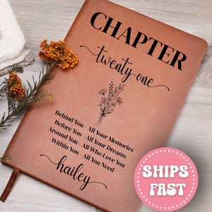 May include: A brown leather journal with the words "CHAPTER twenty-one" in black script. Below the title is a floral design and the text "Behind You - All Your Memories, Before You - All Your Dreams, Around You - All Who Love You, Within You - All You Need, hailey."
