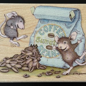 May include: A wooden block featuring an illustration of two cartoon mice with a bag of coffee beans. The bag reads "COFFEE Sumatran BEANS". A pile of coffee beans is in front of the bag. The illustration is in shades of brown, blue, and beige.