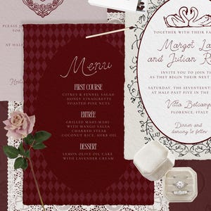 K&ouml;nnte beinhalten: Eine Hochzeitseinladungssuite mit einer weinroten Men&uuml;karte mit Rautenmuster und floralem Rand. Die Einladung enth&auml;lt die Namen Margot La und Julian Rhod, mit einer Schwan-Illustration. Eine Rose und Ringboxen sind ebenfalls vorhanden.