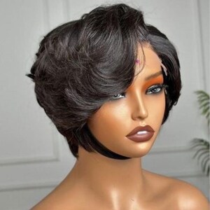 May include: A short, dark brown wig with a side parting and layered style. The wig has a natural-looking hairline and is styled with soft waves. The wig is designed to be worn by anyone.