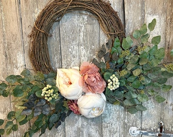 May include: A wreath made of brown twigs with white and pink peonies and green leaves.