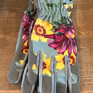May include: A pair of gray gardening gloves with a floral print featuring yellow, red, and white flowers. The gloves have a  Burgon & Ball logo on the wrist.
