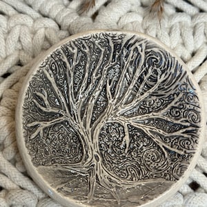 May include: A white ceramic dish with a black and white tree design. The tree is stylized and has a swirling pattern.