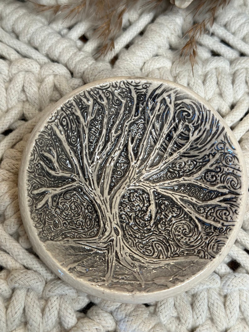 May include: A white ceramic dish with a black and white tree design. The tree is stylized and has a swirling pattern.