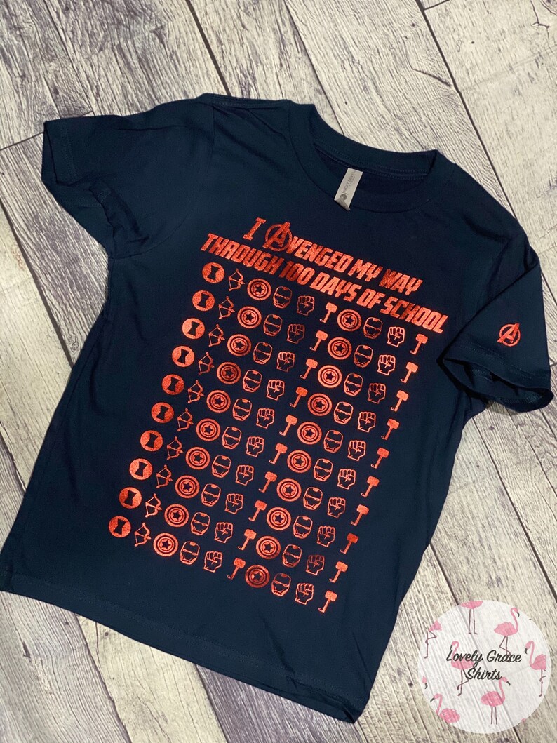 May include: A navy blue t-shirt with a red graphic of the Avengers logo and the text "I AVENGED MY WAY THROUGH 100 DAYS OF SCHOOL". The graphic is a repeating pattern of the Avengers characters' symbols.