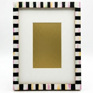 Pu&ograve; includere: Una cornice rettangolare con un passe-partout bianco e un inserto color oro. La cornice &egrave; dipinta con un motivo a righe bianche e nere, accentuato da colori pastello. La cornice &egrave; progettata per contenere una fotografia o un'opera d'arte.