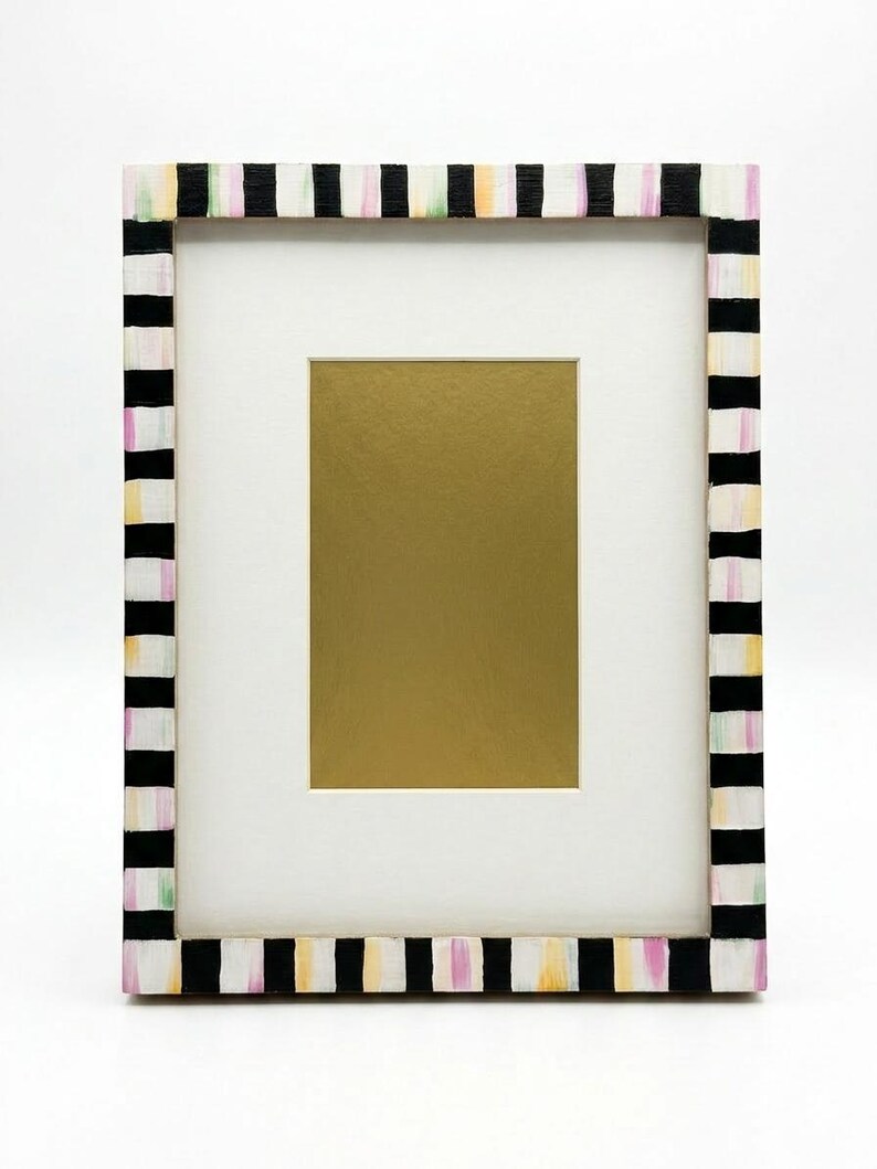 Pu&ograve; includere: Una cornice rettangolare con un passe-partout bianco e un inserto color oro. La cornice &egrave; dipinta con un motivo a righe bianche e nere, accentuato da colori pastello. La cornice &egrave; progettata per contenere una fotografia o un'opera d'arte.