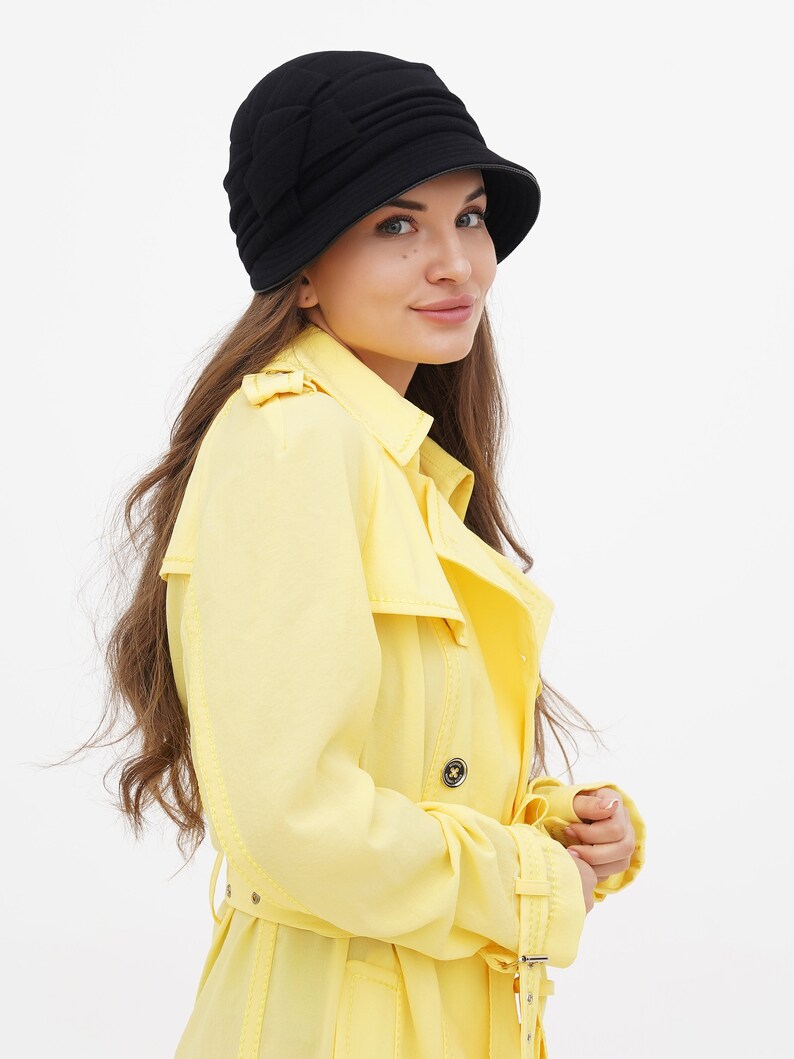 Woman in a black cloche hat, elegantly tilting her head, against a white background.