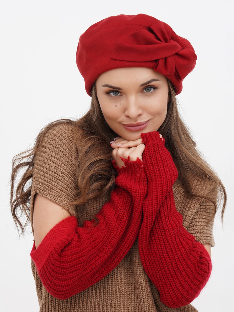 Woman in a red beret with a bow, set against a white background.