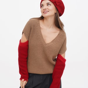 Close-up of a woman in a red beret with a decorative bow, white background.