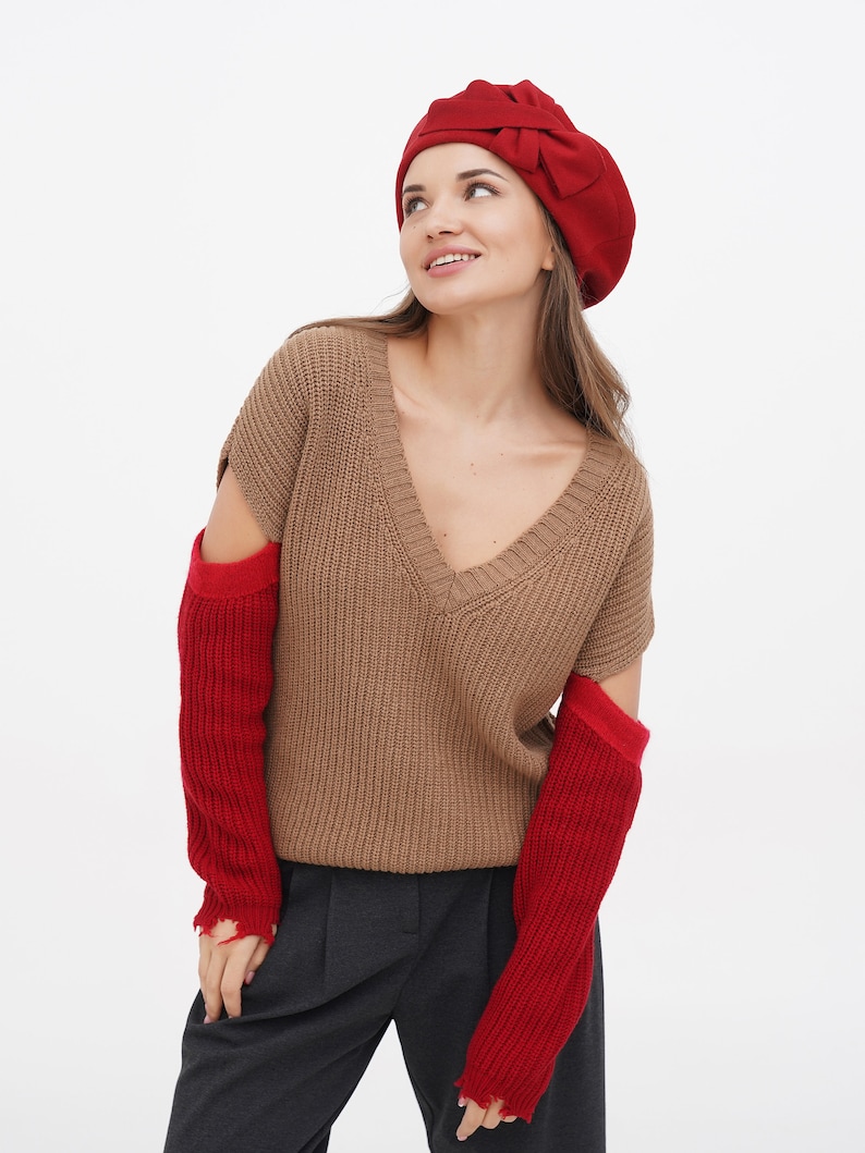 Close-up of a woman in a red beret with a decorative bow, white background.