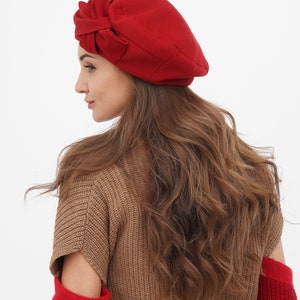 Fashionable woman adorned with a red beret and bow, on a white background.