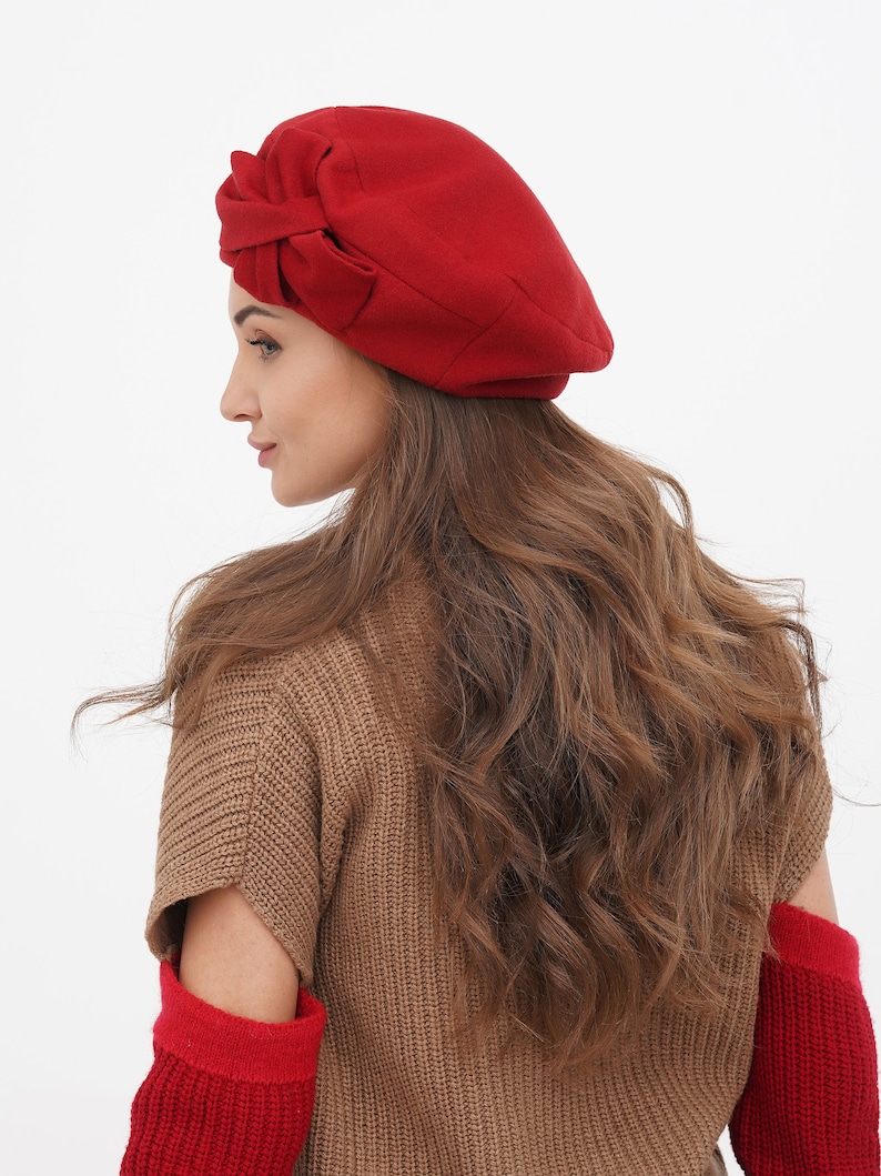 Fashionable woman adorned with a red beret and bow, on a white background.