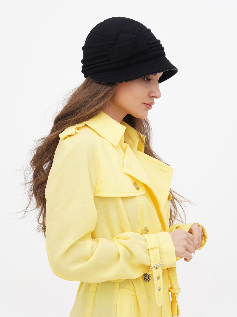 Side view of a woman wearing a black cloche hat, set against a plain white background.