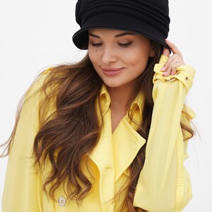 Image of a woman in a black cloche hat, focusing on the hat's fit and style, against a white background.