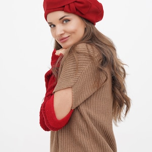 Chic woman in a red beret featuring a bow detail, against a white backdrop.