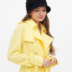 Full-length view of a woman in a black cloche hat, standing against a white background.