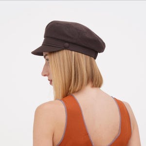Back angle of brown fisherman cap showing how it sits with blonde hair and orange outfit