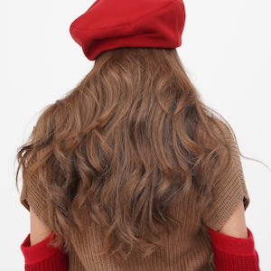 Sophisticated woman in a red beret with a bow, against a plain white background.