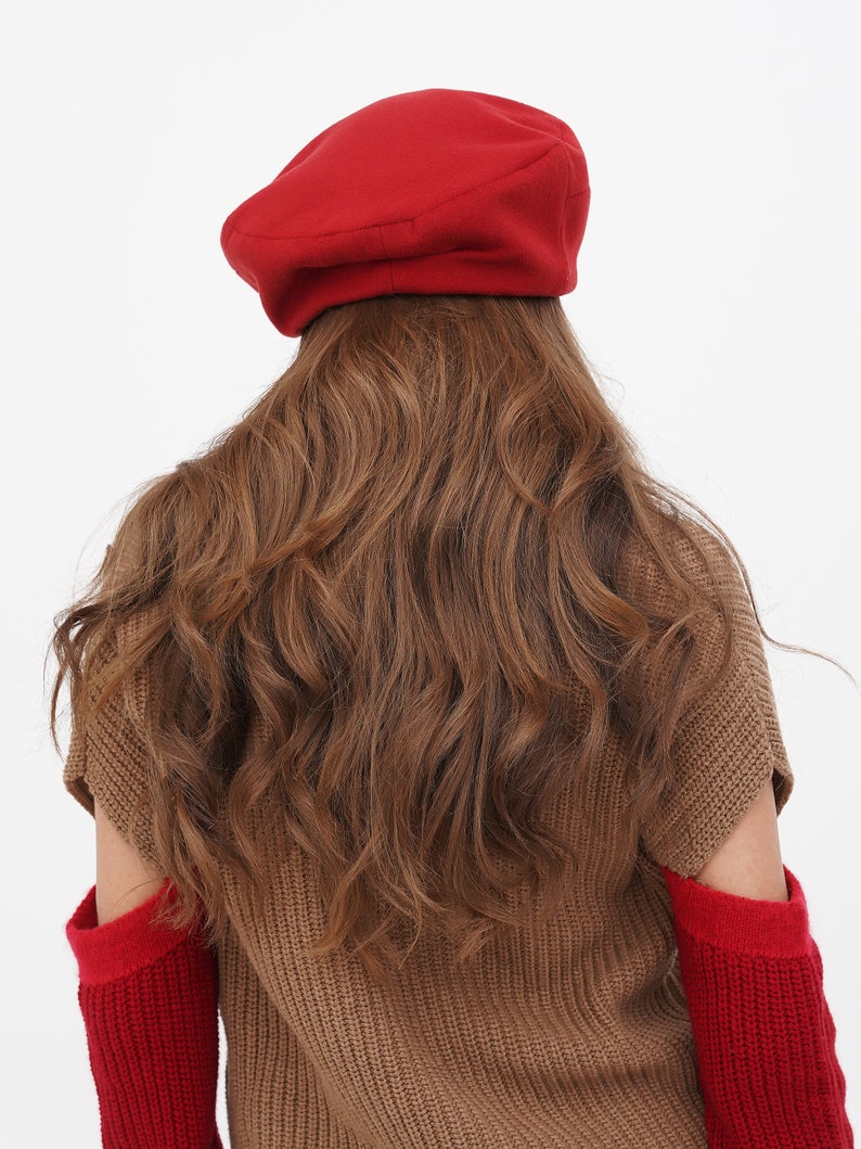 Sophisticated woman in a red beret with a bow, against a plain white background.