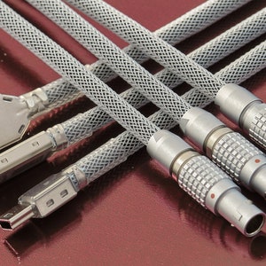 May include: Five cables with different connectors, including USB, micro USB, and three silver connectors with a textured pattern. The cables are covered in a grey mesh.