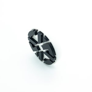 K&ouml;nnte beinhalten: Runder Aufkleber mit einem geometrischen Design in Schwarz und Wei&szlig;.