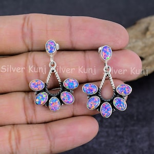 May include: A pair of silver dangle earrings with a teardrop design. Each earring features six oval-shaped pink and purple opal stones.