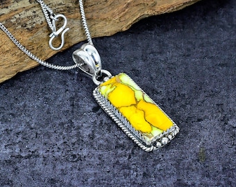 May include: Silver pendant necklace featuring a rectangular yellow and white stone. The stone is set in a silver frame with a rope-like border and small silver beads. The necklace has a silver chain with a hook clasp.