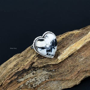 Può includere: Un anello a forma di cuore con una pietra bianca e nera incastonata in argento sterling. La pietra presenta un motivo unico di vortici neri e bianchi.