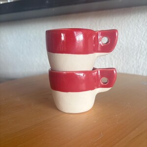 Peut inclure: Ensemble de trois tasses en céramique avec une finition mate et mouchetée. Les tasses sont de couleur crème, gris clair et gris foncé. Chaque tasse a un design simple et minimaliste, idéal pour le café ou le thé.
