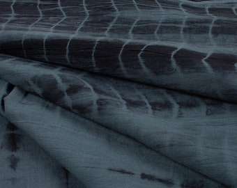 Puede incluir: Un primer plano de una tela azul y negra con estampado tie-dye. La tela tiene una textura suave y arrugada y un brillo sutil.