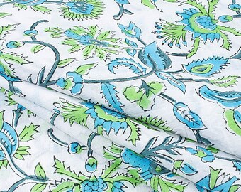 May include: White fabric with a blue and green floral pattern. The fabric is folded in half and the pattern is visible on both sides.