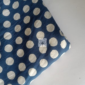 May include: A blue fabric with white polka dots. The fabric is folded in half and the polka dots are a slightly off-white color.